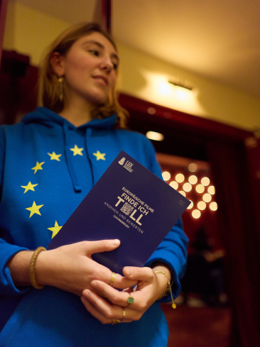 EP-Mitarbeiterin mit EU-Sweat-Shirt und dem LUX-Programm in der Hand.