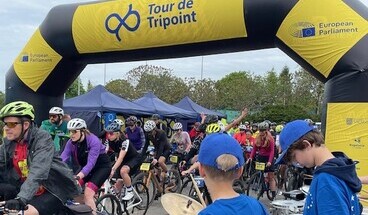 Die Radfahrenden starten die Tour de Triopint und rollen unter Applaus der Schaulustigen durch den Startbogen los.