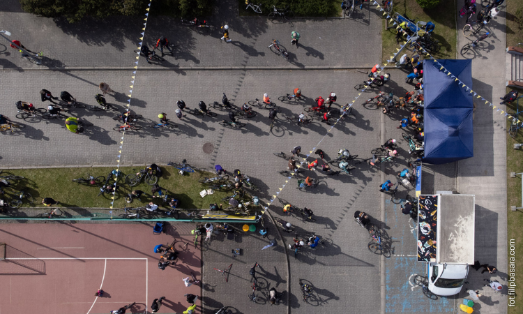 Ein Foto des Geländes in Bogatynia von oben fotografiert. Man sieht den Stand für die Anmeldung, einen Basketballplatz und viele Radfahrende und Zuschauer*innen. 