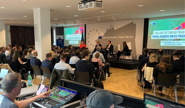 Interessierte sitzen auf Stühlen vor der Podiumsdiskussion und hören zu. 